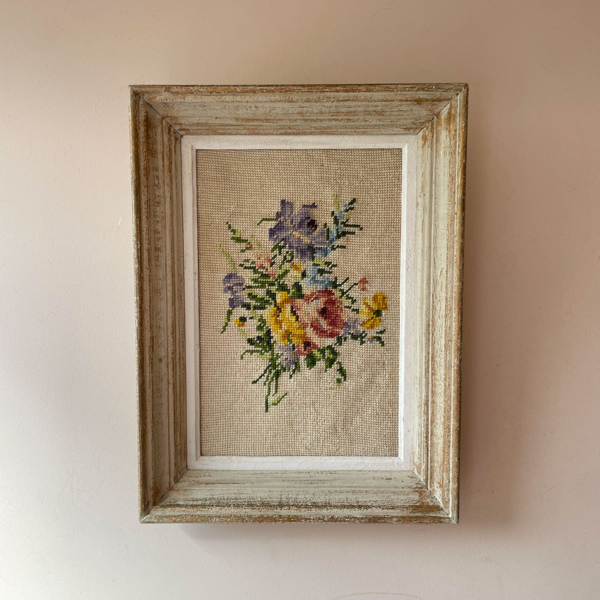Vintage French needlepoint of pink rose, purple and yellow blooms and blue sprigs on oatmeal ground, in distressed frame