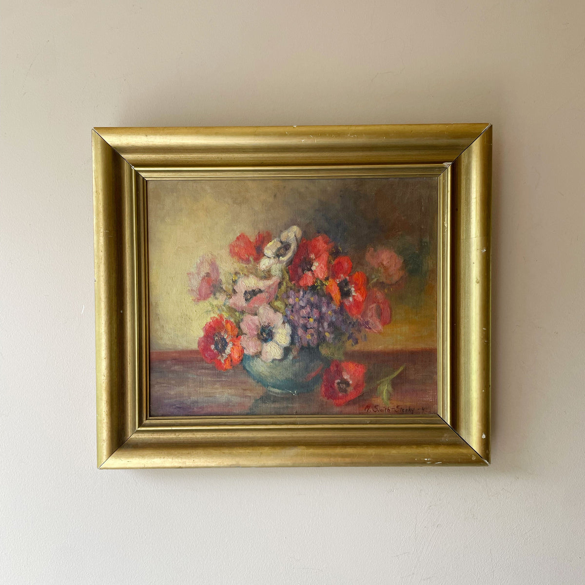Oil still life of red, pink and white anemones with purple violets in a blue bowl on a wooden table, in a gold gilt frame