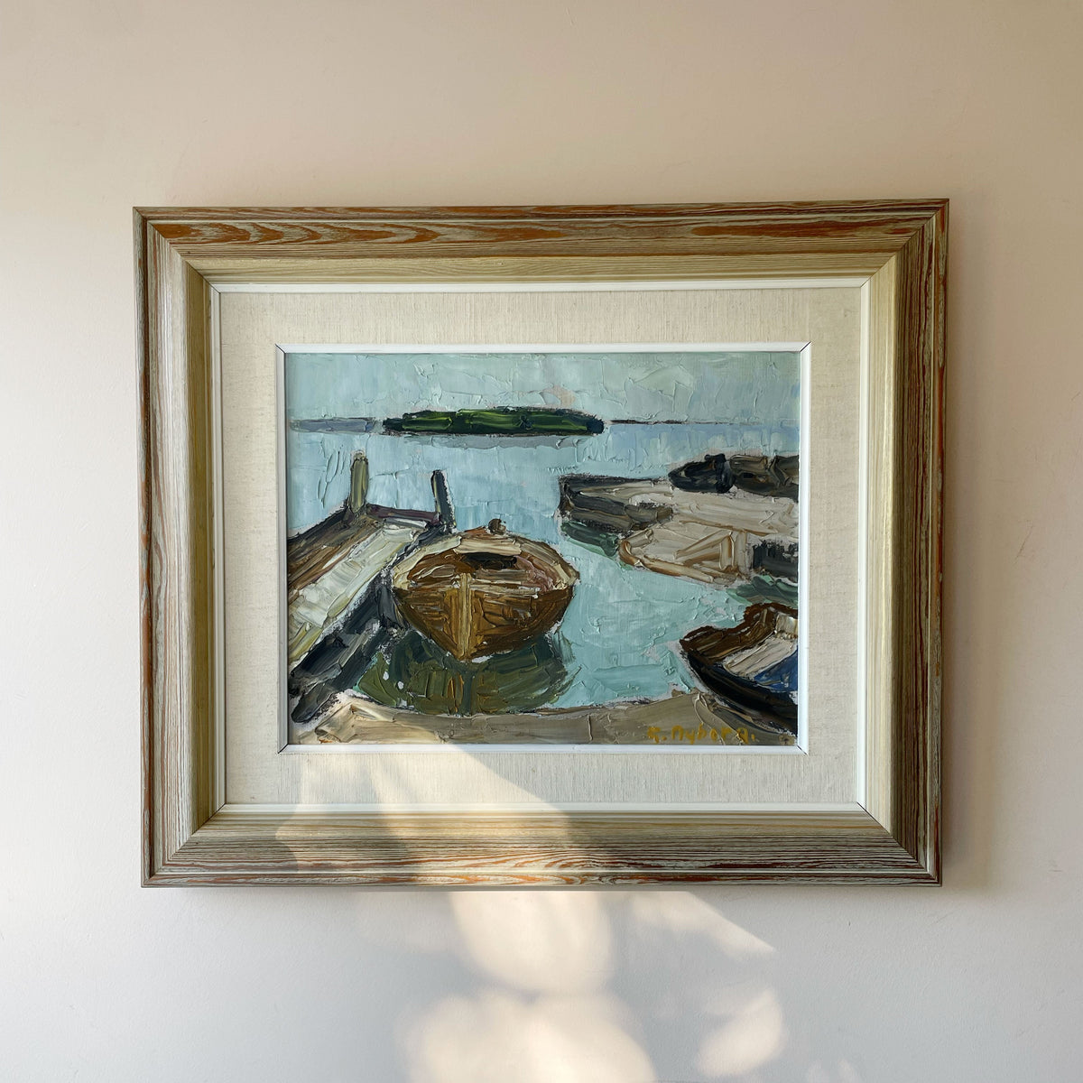 Vintage coastal oil painting of wooden rowing boats moored on calm blue water, thick palette-knife impasto in ochre, white and green, in a limed wood frame.