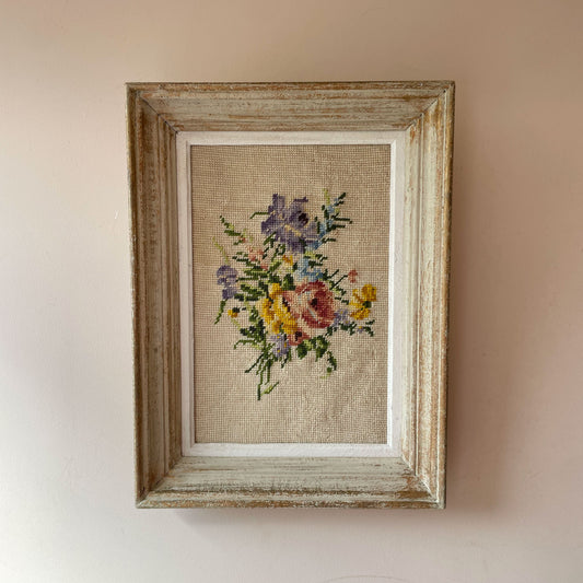 Vintage French needlepoint of pink rose, purple and yellow blooms and blue sprigs on oatmeal ground, in distressed frame